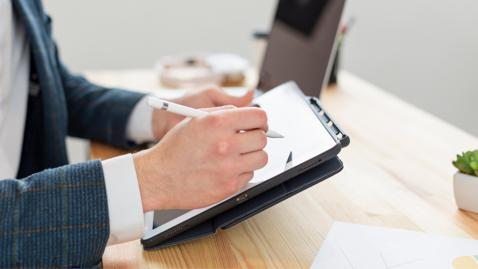 A person completes IRS Form 8825 on a tablet using a digital pen 