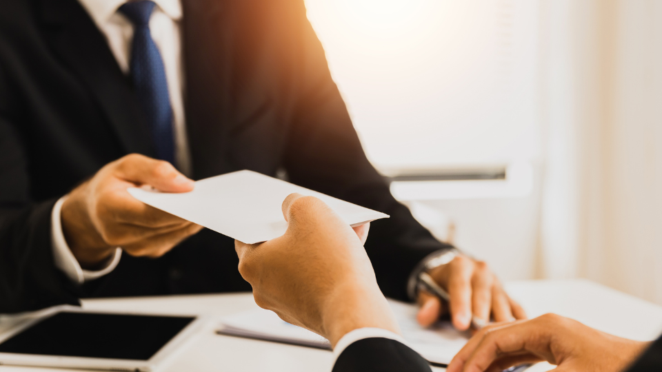 A member of HR hands a bonus check to an employee