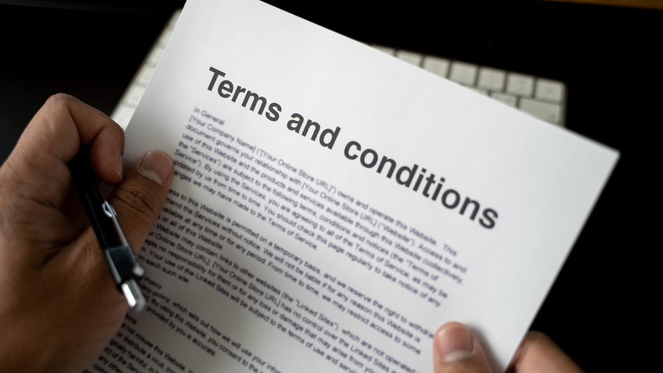A person reviews a loan terms and conditions document with a pen in hand