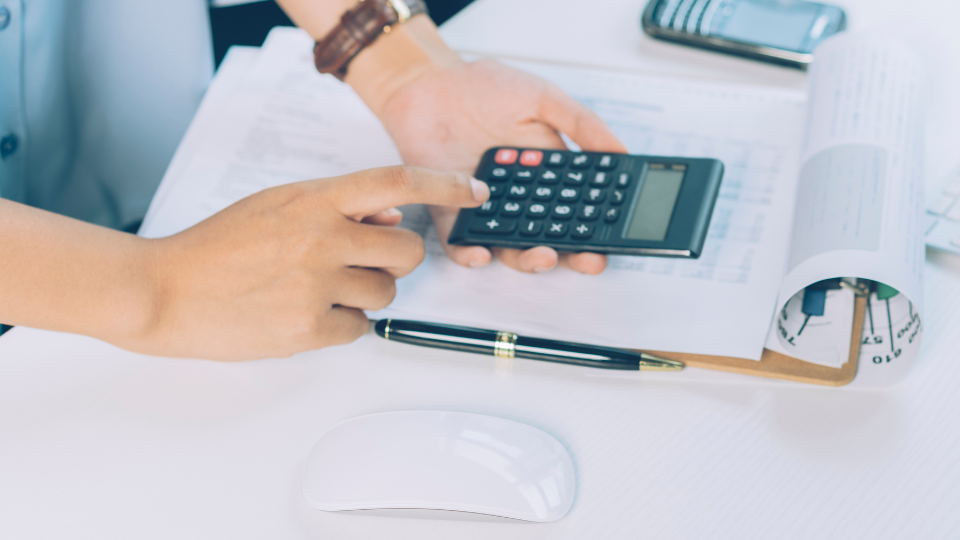 A lender uses a calculator at their desk to calculate asset depletion for a mortgage application
