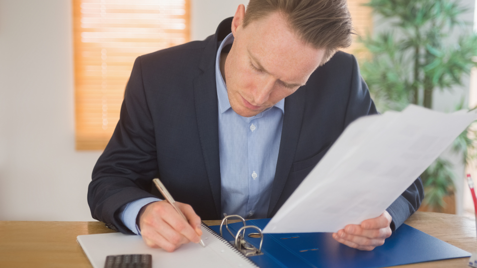 A lender reviews Form 1007 and uses a calculator and pen to assess borrower rental income