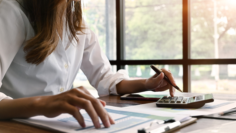 A person sitting at their desk calculates final market rent using a calculator