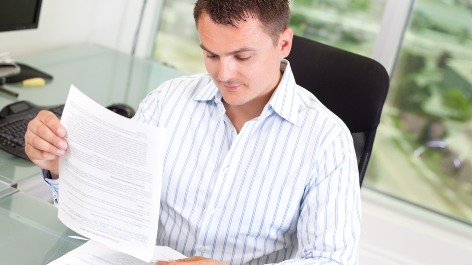 A mortgage underwriter reviews a borrower's financial documents at a desk