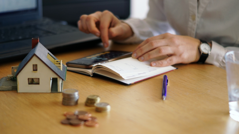 A person at their desk uses a calculator and notes to calculate market rent for Form 1007