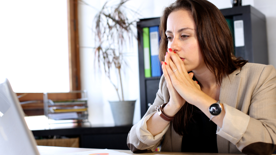 An underwriter looks at their computer in frustration