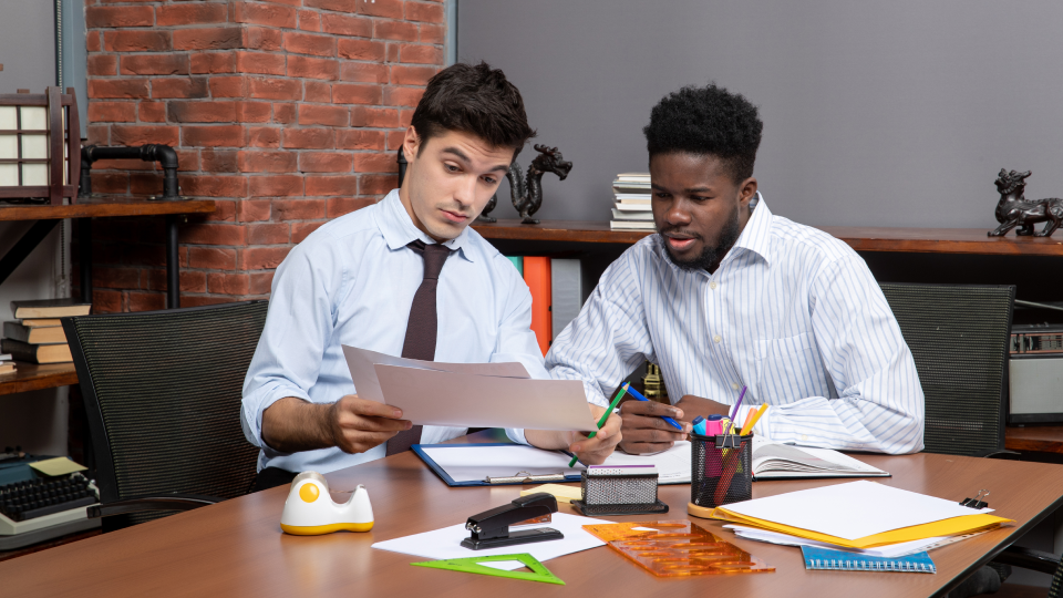 Two business people look at loan documents together